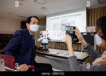 201116 -- SEOUL, 16. November 2020 -- Ein Teilnehmer L eines Bildungsprogramms posiert für Bilder mit LIKU, einem robotischen Lehrveranstalter, in einem Seniorenwohlfahrtszentrum im Bezirk Yangcheon in Seoul, Südkorea, 16. November 2020. Die Metropolitan Government von Seoul arbeitet mit der Seoul Digital Foundation zusammen, um digitale Bildung für Senioren in Seoul zu fördern, die ebenfalls Teil der Robot Promotion and Supply Initiative des südkoreanischen Ministeriums für Handel, Industrie und Energie ist. SÜDKOREA-SEOUL-SENIOR-DIGITAL EDUCATION WANGXJINGQIANG PUBLICATIONXNOTXINXCHN Stockfoto