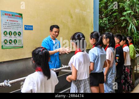 201119 -- NANNING, 19. Nov. 2020 -- Foto vom 8. Juli 2020 zeigt Tao Lei, einen Arzt der ethnischen Gruppe Yao, der die ordnungsgemäße Vorgehensweise der Handwäsche für Schüler im autonomen Kreis Jinxiu Yao in der südchinesischen autonomen Region Guangxi Zhuang veranschaulicht. Der 20. November ist der Weltkindertag. Im Rahmen seiner Armutsbekämpfungskampagne in den letzten Jahren hat Guangxi einen Schritt weiter gegangen, um sicherzustellen, dass Kinder in von Armut betroffenen Gebieten ein besseres Leben und eine bessere Bildung genießen können. CHINA-GUANGXI-NANNING-CHILDREN-ANTI-POVERTYCN CAOXYIMING PUBLICATIONXNOTXINXCHN Stockfoto