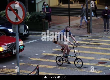 201124 -- HONG KONG, 24. November 2020 -- Ein Mann mit Gesichtsmaske fährt Ein Fahrrad auf einer Straße in Hong Kong, Südchina, 24. November 2020. UM Hongkong ANZUSCHLIESSEN , werden die Maßnahmen zur sozialen Distanzierung verschärft , wobei 80 neue COVID-19-Fälle gemeldet werden . CHINA-HONG KONG-COVID-19-FÄLLE CN LIXGANG PUBLICATIONXNOTXINXCHN Stockfoto