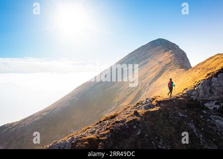 Bergsteigen auf dem Berg, eine junge Frau, die auf dem Weg mit Trekkingstöcken auf dem Bergkamm wandert Stockfoto