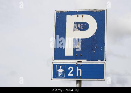 Zwei Stunden kostenloser Parkplatz bei Verwendung einer Parkscheibe auf einem abgenutzten Straßenschild. Stockfoto