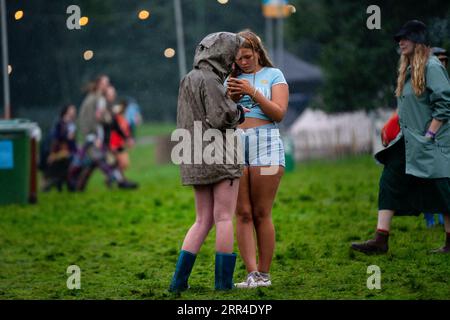 Zwei Teenagermädchen im Regen und Schlamm. Green man Festival, Brecon, Wales, Großbritannien, 2023. Foto: Rob Watkins Stockfoto