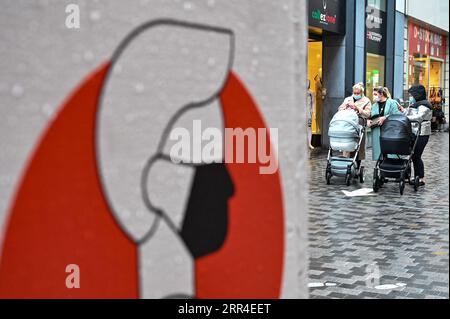 201202 -- PEKING, 2. Dezember 2020 -- Menschen gehen an einem Schild vorbei, das Menschen daran erinnert, Gesichtsmasken an einer Handelsstraße in Brüssel, Belgien, 1. Dezember 2020 zu tragen. XINHUA FOTOS DES TAGES ZhangxCheng PUBLICATIONxNOTxINxCHN Stockfoto