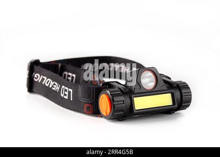 Stirnlampe mit weißer Hintergrundisolierung. Licht batteriebetriebene Lampe am Kopf abgenutzt. Stockfoto