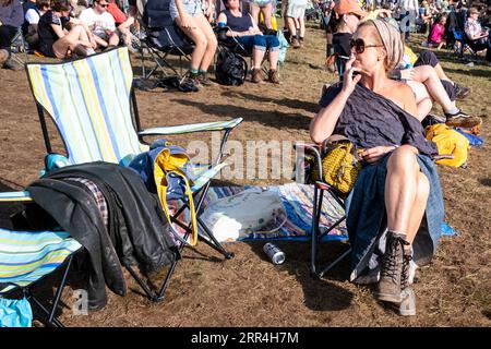 Eine Frau mittleren Alters mit schlammigen Stiefeln raucht eine Roll-up-Zigarette beim Green man Festival, Brecon, Wales, Großbritannien, 2023. Foto: Rob Watkins Stockfoto