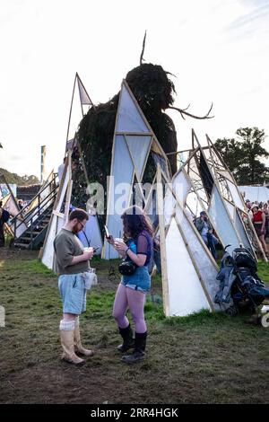 Ein Paar scrollte auf ihren Mobiltelefonen beim Wicker man at Green man Festival, Brecon, Wales, Großbritannien, 2023. Foto: Rob Watkins Stockfoto