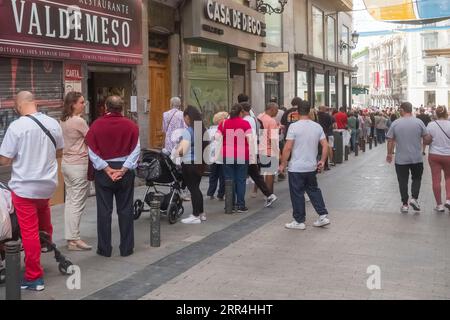 Eine lange Schlange vor dem Büro der Lotto-Agentur Dona Manolita, die darauf wartet, Tickets für die spanische Weihnachtslotterie, El Gordo, Madrid Spanien, zu kaufen. Stockfoto