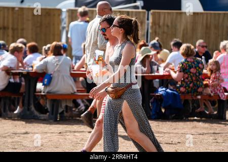 Ein junges Paar spaziert durch den Barbereich mit Bieren beim Green man Festival, Brecon, Wales, Großbritannien, 2023. Foto: Rob Watkins Stockfoto