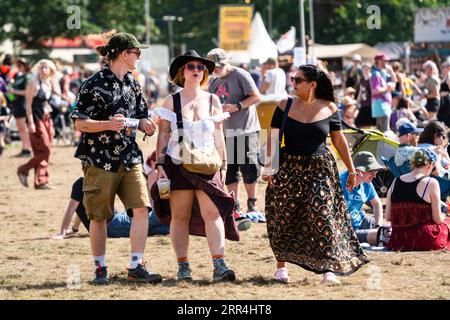 Eine Gruppe junger Freunde spaziert durch den Barbereich mit Bieren beim Green man Festival, Brecon, Wales, Großbritannien, 2023. Foto: Rob Watkins Stockfoto