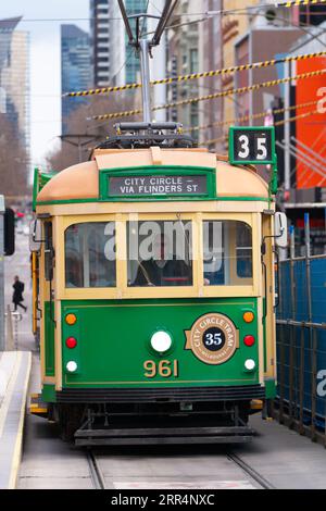 35 Melbourne Tram, eine Vintage Tram der W-Klasse auf dem Stadtkreis, die in eine Straßenbahnhaltestelle fährt, mit der Skyline von Melbourne im Hintergrund. Stockfoto