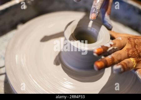 Nahaufnahme der weiblichen Hände bei Töpferarbeiten mit Ton auf einem Töpferrad. Stockfoto