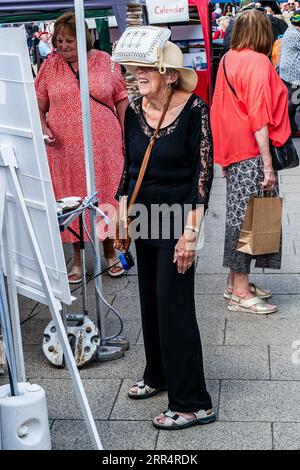 Bridport, Dorset. England. Die Leute feiern das Bridport hat Festival mit phantasievoller Kopfbedeckung. Ein Handtaschenhut. Stockfoto