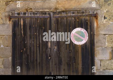 Straßenschild - Parken ist verboten, es ist am Holztor der Gebäudewand angebracht. Stockfoto