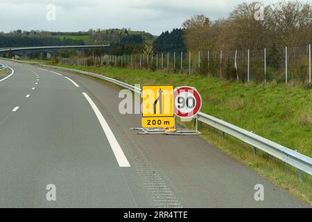 Auf der Autobahn gibt es ein provisorisches Straßenschild - die Verengung der Straße und die Geschwindigkeitsbegrenzung von 90 km/h. Stockfoto