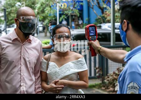 201215 -- MAKATI, 15. Dezember 2020 -- Ein Paar, Das Gesichtsmasken trägt, lässt seine Körpertemperatur während einer maskierten Hochzeit in einem Park in Makati City, Philippinen, 15. Dezember 2020 überprüfen. Die philippinische Regierung hat eine strengere Politik der Gesichtsbedeckung auferlegt, da sie befürchtet, dass es während der Weihnachtszeit zu einem möglichen Anstieg der Fälle kommen könnte. PHILIPPINEN-MAKATI-MASSE MASKIERTE HOCHZEIT RouellexUmali PUBLICATIONxNOTxINxCHN Stockfoto