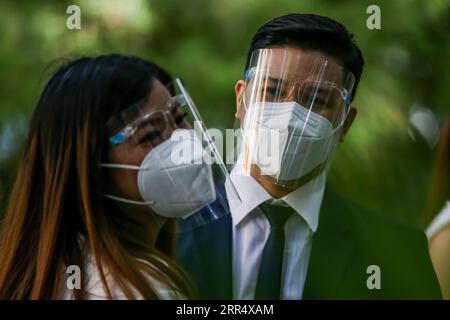 201215 -- MAKATI, 15. Dezember 2020 -- Ein Paar, Das Gesichtsmasken trägt, wird während einer maskierten Hochzeit in einem Park in Makati City, Philippinen, 15. Dezember 2020 gesehen. Die philippinische Regierung hat eine strengere Politik der Gesichtsbedeckung auferlegt, da sie befürchtet, dass es während der Weihnachtszeit zu einem möglichen Anstieg der Fälle kommen könnte. PHILIPPINEN-MAKATI-MASSE MASKIERTE HOCHZEIT RouellexUmali PUBLICATIONxNOTxINxCHN Stockfoto