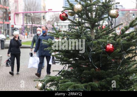 201216 -- BERLIN, 16. Dezember 2020 -- Fußgänger gehen an einem Weihnachtsbaum in Berlin, Hauptstadt von Deutschland, 16. Dezember 2020 vorbei. Deutschland wird ab Mittwoch in eine strengere Sperrung verfallen, nicht unbedingt notwendige Geschäfte schließen und die Größe privater Treffen begrenzen, wie Bundeskanzlerin Angela Merkel und die Staats- und Regierungschefs der Region am Sonntag vereinbart haben. Die strengeren restriktiven Maßnahmen, die bis zum 10. Januar in Kraft sein werden, waren nach einem Strategiepapier eine Reaktion auf einen exponentiellen Anstieg der Zahl der COVID-19-Fälle in Deutschland. ShanYuqi GERMANY-BERLIN-COVID-19-LOCKDOWN ShanxYuqi PUBLICATIONxNOTxINxCHN Stockfoto