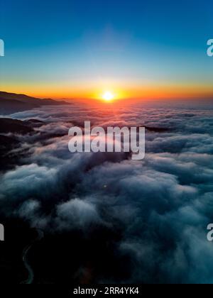 Ein atemberaubender Blick aus der Luft auf einen Sonnenuntergang über den Wolken, der die atemberaubenden Farben des Himmels von tiefem Blau zu leuchtendem Orange einfängt Stockfoto