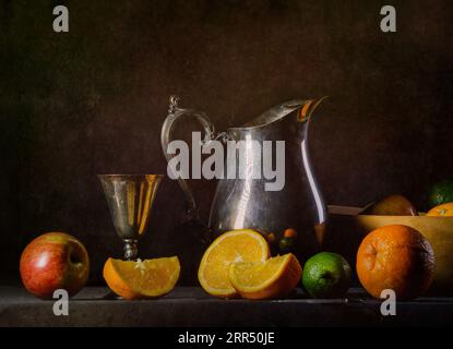 Ein Stillleben mit silbernem Krug, Becher und Früchten mit dramatischer Beleuchtung. Stockfoto
