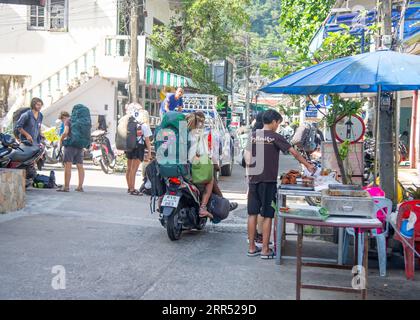 21. März 2023 - Ko Tao Thailand - neu angekommene Touristen, die auf Rollern mit Gepäck auf dem Rücken und zwischen den Beinen fahren Stockfoto