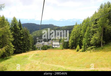 Sessellift für den Transport von Wanderern in den hohen Bergen, die im Sommer den Wald überqueren Stockfoto