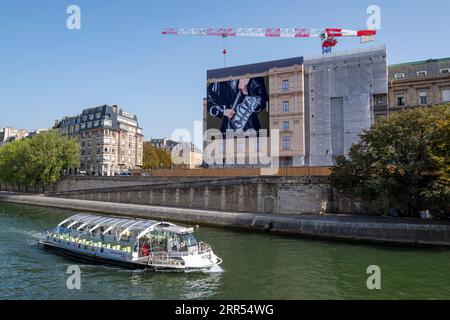 Große Gucci-Werbetafel, die die Gerüste der Renovierungsarbeiten eines Pariser Gebäudes bedeckt. Ein Boot auf der seine im Vordergrund Stockfoto