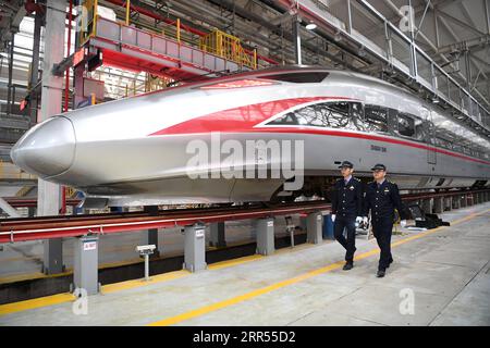 201223 -- CHONGQING, 23. Dezember 2020 -- zwei Mechaniker laufen an einem Fuxing-Kugelzug CR400AF an einer Wartungsstation des Bahnbetriebswerks in der westchinesischen Gemeinde Chongqing, 23. Dezember 2020 vorbei. Der Fuxing-Hochgeschwindigkeitszug CR400AF, der erstmals der Chongqing Railway zugewiesen wurde, debütierte am Mittwoch in Chongqing und soll am Donnerstag mit dem Zug vom Bahnhof Shapingba in Chongqing zum Bahnhof Chengdu East in Chengdu in der westchinesischen Provinz Sichuan in Betrieb genommen werden. Die Fahrt zwischen den beiden Städten wird von 78 Minuten auf 62 Minuten verkürzt. CHINA-CHONGQING-FUXING-KUGELZUG-CR400AF Stockfoto