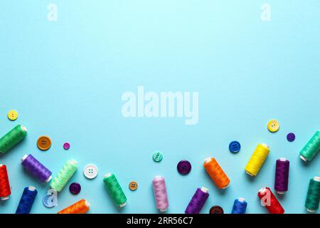 Komposition mit bunten Fadenspulen und Knöpfen auf farbigem Hintergrund Stockfoto