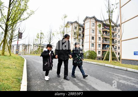 201229 -- BIJIE, 29. Dezember 2020 -- Li Changde C bringt seine Enkelkinder Li Siyu R und Li Qingyi nach der Schule zu Fuß nach Hause in eine neu errichtete Gemeinde zur Armutsbekämpfung Umzug in der alten Gemeinde Shexiang im Dafang County, Provinz Guizhou im Südwesten Chinas, 23. Dezember 2020. Li Siyu, 8, und seine 6-jährige Schwester Li Qingyi, lebten früher im Dorf Hetou als Mitglieder eines armutsgeplagten Haushalts. Sie mussten jeden Tag fast eine Stunde zur Schule laufen. Ihre Eltern arbeiteten in anderen Städten und Li Changde, der 68-jährige Großvater, übernahm die Verantwortung, sie nach und nach zu bringen Stockfoto