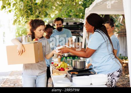 Eine Gruppe von Freiwilligen, die gerne Nahrung an Bedürftige verteilen. Lächeln und echtes Glück überall, während sie Obdachlose und Senioren, die von Armut betroffen sind, spenden. Stockfoto