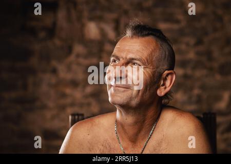 Ein zufriedener älterer Mann, sechzig Jahre alt, lächelt und schaut auf die Kamera. Stockfoto