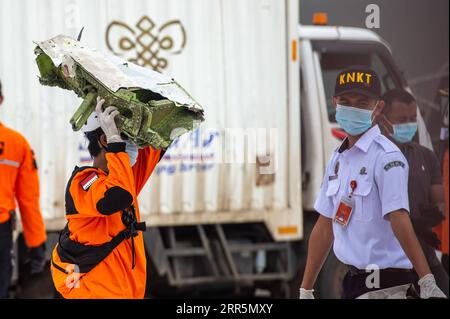 210111 -- JAKARTA, 11. Januar 2021 -- Mitarbeiter tragen Trümmer, die während der Suche im Such- und Rettungskommando am Tanjung Priok Hafen in Jakarta, Indonesien, am 11. Januar 2021 gefunden wurden. Indonesiens Such- und Rettungsteam hat das Einsatzgebiet erweitert, um nach Trümmern und Opfern des Flugzeugabsturzes Sriwijaya mit weiteren Flotten am dritten Tag der Operation zu suchen, sagte die indonesische nationale Such- und Rettungsagentur am Montag. Bis jetzt haben die Offiziere die Trümmer des unglückseligen Flugzeugs und Leichenteile, die Eigentum der Opfer sind, gefunden und den Standort der schwarzen Boxen geschätzt. Stockfoto