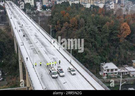 210111 -- PANZHOU, 11. Januar 2021 -- Luftaufnahme am 11. Januar 2021 zeigt Verkehrspolizisten, die auf der Elangpu-Brücke in der Stadt Panzhou in der südwestlichen chinesischen Provinz Guizhou Eis schmelzen. Die jüngste starke kalte Welle hat zu Kongelationen in Panzhou und an vielen anderen Orten in Guizhou geführt. Rund 400 Verkehrspolizisten in Panzhou arbeiten nun rund um die Uhr daran, die Straßenflächen der Stadt zu entfernen. Das fluoreszierende Grün auf ihren Jacken scheint die wärmste Farbe in einem frostigen Winter zu sein. CHINA-GUIZHOU-PANZHOU-POLICE-ICE-MELTING CN OUXDONGQU PUBLICATIONXNOTXINXCHN Stockfoto