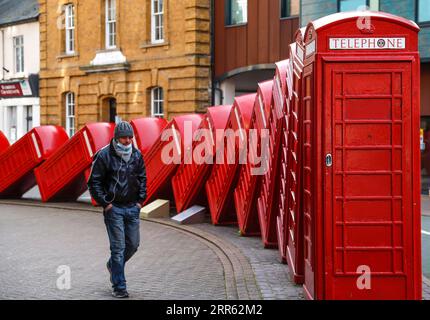 210123 -- PEKING, 23. Januar 2021 -- Ein Mann geht am 21. Januar 2021 an einer Skulptur roter Telefonkästen mit dem Titel Out of Order in Kingston upon Thames, Großbritannien vorbei. XINHUA-FOTOS DES TAGES HanxYan PUBLICATIONxNOTxINxCHN Stockfoto