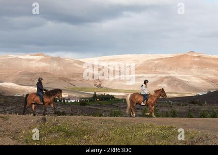 Myvatn Lake, Island - 31. Juli 2016: Ein paar Touristen reiten auf isländischen Pferden in braunen und schwarzen Farben. Islandpferde an einem hellen Sommertag mit Stockfoto