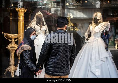 210128 -- TEHERAN, 28. Januar 2021 -- die Leute schauen sich die Schaufensterausstellung in einem Hochzeitskleiderladen in Teheran, Iran, am 28. Januar 2021 an. Für viele Iraner, die den Knoten binden wollen, waren sie gezwungen, ihre Hochzeitspläne zu ändern und anzupassen, da sie mit Hindernissen konfrontiert waren, die durch die COVID-19-Pandemie verursacht wurden. Foto von /Xinhua IRAN-TEHRAN-COVID-19-WEDDING PLAN-CHANGE AhmadxHalabisaz PUBLICATIONxNOTxINxCHN Stockfoto