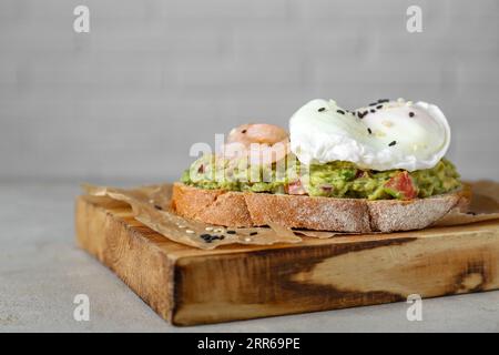 Köstliches Sandwich mit Guacamole, Garnelen und Spiegelei auf hellgrauem Tisch, Nahaufnahme Stockfoto