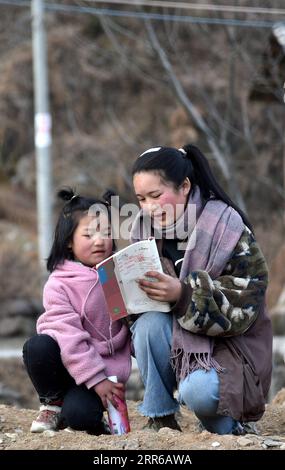 210203 -- LIANGSHAN, 3. Februar 2021 -- Wuqi Labumu R, die älteste Tochter von Bamu Yubumu, liest mit ihrer jüngeren Schwester im Dorf Taoyuan, Kreis Yuexi, Autonome Präfektur Liangshan Yi, Provinz Sichuan im Südwesten Chinas, 20. Januar 2021. Eine junge Mutter beugte sich mühsam nach vorne, um das Gewicht eines übergroßen Gepäcks auf ihrem Rücken und ein winziges Baby in ihrem Arm auszugleichen, während sie ihre Schritte vorwärts kämpfte. Dies war das Bild, das der Xinhua-Reporter in der Nähe des Nanchang-Bahnhofs in Nanchang, der ostchinesischen Provinz Jiangxi, am 30. Januar 2010 aufgenommen hat. Das Foto mit dem Titel Baby, Mom nimmt dich nach Hause berührte die Herzen Stockfoto