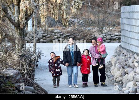 210203 -- LIANGSHAN, 3. Februar 2021 -- Bamu Yubumu spaziert mit ihren Kindern auf einer neu gepflasterten Betonstraße im Dorf Taoyuan, Kreis Yuexi, Autonome Präfektur Liangshan Yi, Provinz Sichuan im Südwesten Chinas, 22. Januar 2021. Eine junge Mutter beugte sich mühsam nach vorne, um das Gewicht eines übergroßen Gepäcks auf ihrem Rücken und ein winziges Baby in ihrem Arm auszugleichen, während sie ihre Schritte vorwärts kämpfte. Dies war das Bild, das der Xinhua-Reporter in der Nähe des Nanchang-Bahnhofs in Nanchang, der ostchinesischen Provinz Jiangxi, am 30. Januar 2010 aufgenommen hat. Das Foto mit dem Titel Baby, Mom nimmt dich nach Hause berührte die Herzen von Millionen W Stockfoto