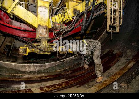 210207 -- ÜRÜMQI, 7. Februar 2021 -- Ein Arbeiter trägt einen Stahlbogenrahmen am Boden des harten Felsenschneidwerks auf der Baustelle des Tianshan-Shmingham-Tunnels in der nordwestlichen chinesischen autonomen Region Xinjiang Uygur, 4. Februar 2021. Der Tianshan-Shdak-Tunnel ist mit einer Gesamtlänge von etwa 22 Kilometern der derzeit längste im Bau befindliche Autobahntunnel in China. Der 2020 begonnene Tunnel, ein sechsjähriges Projekt auf der Urumqi-Yuli-Autobahn, durchquert eine kalte und hochgelegene Zone mit rauem Klima und geologischen Bedingungen. Nach der Fertigstellung und der Öffnung für den Verkehr bietet es mehr Sicherheit und mehr Sicherheit Stockfoto