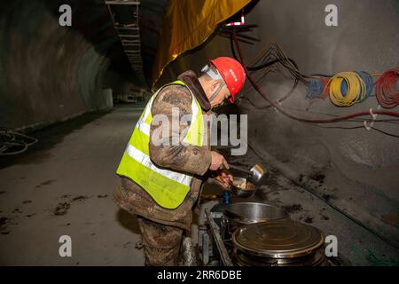 210207 -- ÜRÜMQI, 7. Februar 2021 -- Ein Arbeiter isst auf der Baustelle des Tianshan-Shdeparture-Tunnels in der nordwestchinesischen autonomen Region Xinjiang Uygur, 4. Februar 2021. Der Tianshan-Shdak-Tunnel ist mit einer Gesamtlänge von etwa 22 Kilometern der derzeit längste im Bau befindliche Autobahntunnel in China. Der 2020 begonnene Tunnel, ein sechsjähriges Projekt auf der Urumqi-Yuli-Autobahn, durchquert eine kalte und hochgelegene Zone mit rauem Klima und geologischen Bedingungen. Nach der Fertigstellung und der Öffnung für den Verkehr wird es den Passagieren eine sicherere und bequemere Reise ermöglichen und l fördern Stockfoto