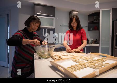 210211 -- CANBERRA, 11. Februar 2021 -- Foto vom 8. Februar 2021 zeigt Youmei Peng L und ihre Tochter, die zusammen Knödel machen, um das chinesische Neujahr in Canberra, Australien, zu feiern. Knödel machen, Couplets aufhängen, traditionelle Tänze aufführen... die Chinesen in der australischen Hauptstadt Canberra finden verschiedene Möglichkeiten, um eine Atmosphäre für das Frühlingsfest zu schaffen. ZUM Chinesischen Neujahr in der australischen Hauptstadt gefeiert mit Klößen, Couplets und Wünschen der Rückkehr nach China bald Foto von /Xinhua AUSTRALIA-CANBERRA-CHINESE LUNAR NEUJAHRSFEIER ChuxChen PUBLICATIONxNOTxINxCHN Stockfoto