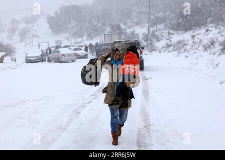 210218 -- AJLOUN, 18. Februar 2021 -- Eine Frau, die ihr Kind trägt, spaziert am 17. Februar 2021 im Schnee in Ajloun, Jordanien. Ein Schneesturm am Mittwoch traf Jordans bergige Gebiete, begleitet von starken Winden und kaltem Wetter. Foto von /Xinhua JORDAN-AJLOUN-SNOWSTORM MohammadxAbuxGhosh PUBLICATIONxNOTxINxCHN Stockfoto