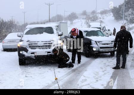 210218 -- AJLOUN, 18. Februar 2021 -- Leute überprüfen ein Auto, das im Schnee in Ajloun, Jordanien, am 17. Februar 2021 feststeckt. Ein Schneesturm am Mittwoch traf Jordans bergige Gebiete, begleitet von starken Winden und kaltem Wetter. Foto von /Xinhua JORDAN-AJLOUN-SNOWSTORM MohammadxAbuxGhosh PUBLICATIONxNOTxINxCHN Stockfoto