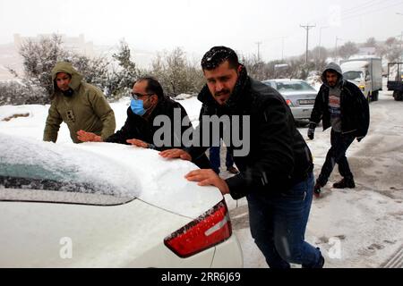 210218 -- AJLOUN, 18. Februar 2021 -- Leute schieben ein Auto in Ajloun, Jordanien, am 17. Februar 2021. Ein Schneesturm am Mittwoch traf Jordans bergige Gebiete, begleitet von starken Winden und kaltem Wetter. Foto von /Xinhua JORDAN-AJLOUN-SNOWSTORM MohammadxAbuxGhosh PUBLICATIONxNOTxINxCHN Stockfoto