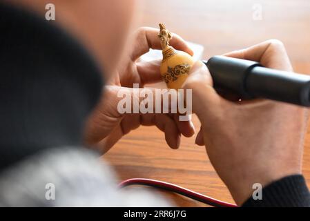 210218 -- HORGOS, 18. Februar 2021 -- Cao Guangyao arbeitet in seinem Atelier in Horgos, Nordwestchinas autonomer Region Xinjiang Uygur, am 6. Februar 2021 an pyrographischen Kalabasarbeiten. Cao Guangyao ist ein 45-jähriger Bauer in Horgos. Er ist auch bei den Einheimischen als Künstler für seine pyrographische Kalabaskunst bekannt. Cao interessierte sich vor 8 Jahren für pyrografische Kreationen aus Fernsehsendungen und begann seitdem mit seiner eigenen Schöpfung. Trotz fehlender Berufsausbildung unternahm Cao immer wieder Kunstversuche mit Liebe und Leidenschaft in der Slacksaison der landwirtschaftlichen Produktion. N Stockfoto