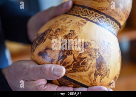 210218 -- HORGOS, 18. Februar 2021 -- Cao Guangyao überprüft pyrographische Kalabaskunst in seinem Atelier in Horgos, Nordwestchinas autonome Region Xinjiang Uygur, 6. Februar 2021. Cao Guangyao ist ein 45-jähriger Bauer in Horgos. Er ist auch bei den Einheimischen als Künstler für seine pyrographische Kalabaskunst bekannt. Cao interessierte sich vor 8 Jahren für pyrografische Kreationen aus Fernsehsendungen und begann seitdem mit seiner eigenen Schöpfung. Trotz fehlender Berufsausbildung unternahm Cao immer wieder Kunstversuche mit Liebe und Leidenschaft in der Slacksaison der landwirtschaftlichen Produktion. Jetzt Stockfoto