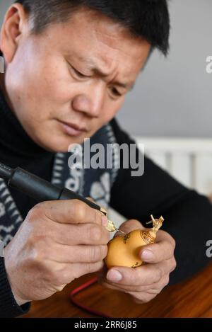 210218 -- HORGOS, 18. Februar 2021 -- Cao Guangyao arbeitet in seinem Atelier in Horgos, Nordwestchinas autonomer Region Xinjiang Uygur, am 6. Februar 2021 an pyrographischen Kalabasarbeiten. Cao Guangyao ist ein 45-jähriger Bauer in Horgos. Er ist auch bei den Einheimischen als Künstler für seine pyrographische Kalabaskunst bekannt. Cao interessierte sich vor 8 Jahren für pyrografische Kreationen aus Fernsehsendungen und begann seitdem mit seiner eigenen Schöpfung. Trotz fehlender Berufsausbildung unternahm Cao immer wieder Kunstversuche mit Liebe und Leidenschaft in der Slacksaison der landwirtschaftlichen Produktion. N Stockfoto