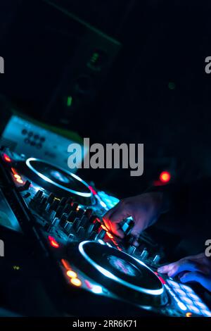 Nahaufnahme der DJ-Hände, die auf der DJ-Mischkonsole auf der Nachtclub-Party verschiedene Track-Bedienelemente spielen. Stockfoto