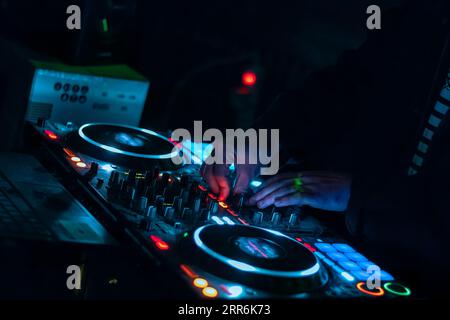 Nahaufnahme der DJ-Hände, die auf der DJ-Mischkonsole auf der Nachtclub-Party verschiedene Track-Bedienelemente spielen. Stockfoto